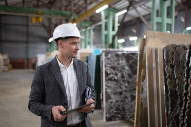 Businessman picking materials in stone warehouse - CAVF91136