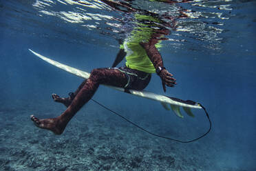 Männlicher Surfer auf dem Surfbrett sitzend in der Unterwasserwelt der Malediven - KNTF05960