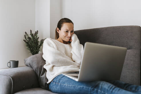 Caucasian woman watching video on laptop at home - DMGF00331