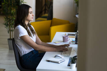 Junge Geschäftsfrau beim Tippen auf der Computertastatur im Büro - GIOF09817