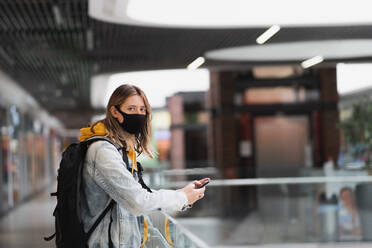 Frau mit Maske in einem Einkaufszentrum oder in der U-Bahn mit Blick auf eine Kamera - CAVF91166
