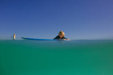 Siblings paddleboard in turquoise waters of Hawaii - CAVF91260
