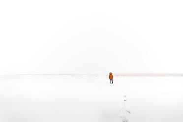 Junge geht durch den Schnee zu einem offenen Feld auf dem Land - CAVF91264