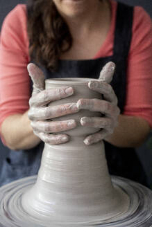 Close up of hands making a ceramic pot - CAVF91267