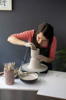 Young woman working clay in ceramic studio - CAVF91268