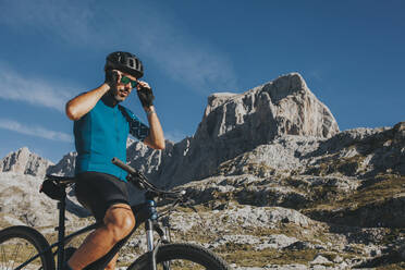 Männlicher Radfahrer mit Sonnenbrille im Nationalpark Picos de Europa an einem sonnigen Tag, Kantabrien, Spanien - DMGF00353