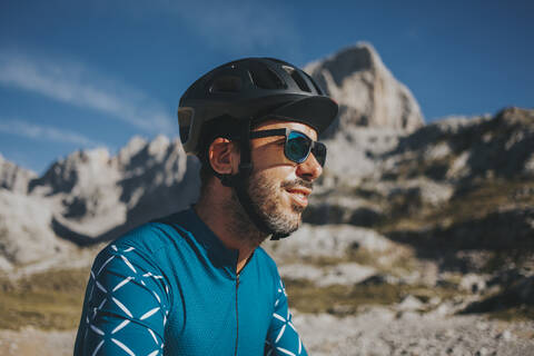 Cyclist wearing sunglasses and cycling helmet at Picos de Europa National Park on sunny day, Cantabria, Spain stock photo