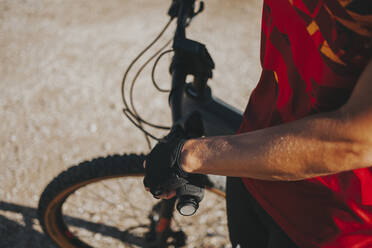 Hand of female cyclist holding bicycle handle on sunny day, Picos de Europa National Park, Cantabria, Spain - DMGF00363