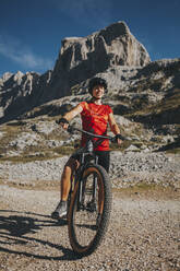 Radfahrerin mit Fahrrad am Berg im Nationalpark Picos de Europa, Kantabrien, Spanien - DMGF00364