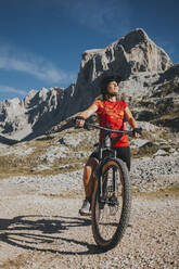 Lächelnde Radfahrerin mit geschlossenen Augen auf dem Fahrrad im Nationalpark Picos de Europa, Kantabrien, Spanien - DMGF00365