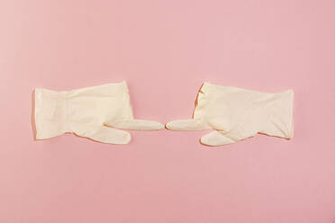 Studioaufnahme eines Paars chirurgischer Handschuhe, die sich mit den Zeigefingern berühren - MAUF03648