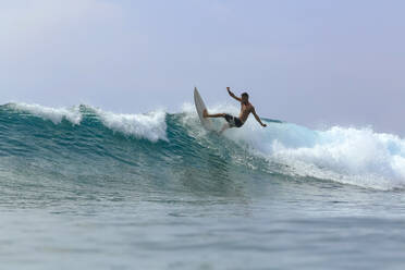 Mann mit Surfbrett surft auf Welle gegen klaren Himmel - KNTF06003