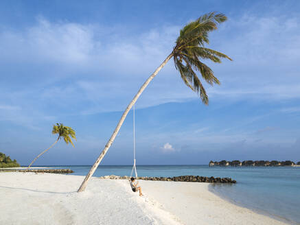 Frau schwingt an einem Seil gegen das Meer am Strand, Bali - KNTF06010