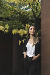 Confident businesswoman with hands in pockets leaning on wall - MTBF00711