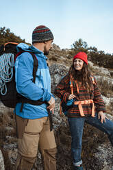 Heterosexual couple hiking together on rock mountain during vacation - RCPF00402