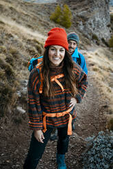 Lächelnde Frau beim Wandern mit ihrem Freund auf einem felsigen Berg im Urlaub - RCPF00407