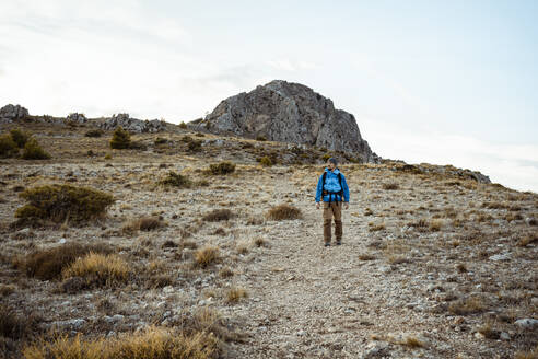 Mittlerer erwachsener Mann, der beim Wandern auf einem Felsenberg im Urlaub wegschaut - RCPF00409