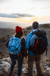 Heterosexuelles Paar betrachtet den Sonnenuntergang beim Wandern im Urlaub - RCPF00416