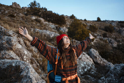 Glückliche Frau mit ausgestreckten Armen auf einem Berg stehend im Urlaub - RCPF00425