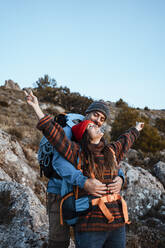 Glücklicher Freund umarmt Freundin stehend mit ausgestreckten Armen auf Berg im Urlaub - RCPF00426