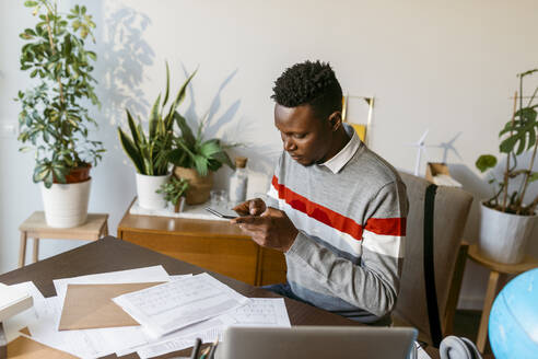 Männlicher Finanzberater fotografiert Kontodokument auf dem Schreibtisch im Büro zu Hause - VABF04084