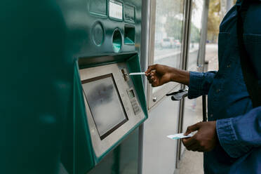 Businessman buying ticket while inserting credit card through machine - VABF04132