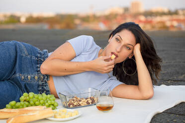 Schöne Frau isst Käse, liegt auf dem Dach beim Picknick - NGF00721