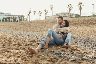 Girlfriend and boyfriend spending leisure time while sitting on sand at beach - VABF04156