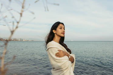 Contemplating woman with arms crossed against sky at beach - VABF04173