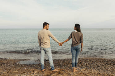 Junge Freundin und Freund halten Hände am Strand - VABF04191