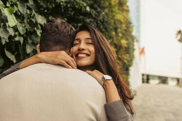 Lächelnde Freundin umarmt ihren Freund im Park - VABF04207