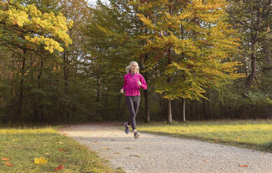 Frau joggt im Park gegen Bäume - FCF01920