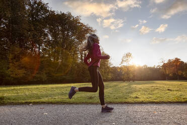 Young woman running outdoors in a city park on a cold fall - Stock Image -  Everypixel