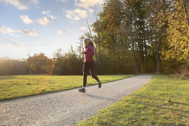 Young woman running outdoors in a city park on a cold fall - Stock Image -  Everypixel