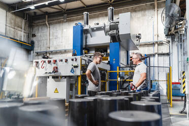 Young male engineer listening to mature coworker during meeting in industry - DIGF13453