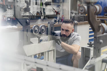 Professioneller männlicher Ingenieur, der sich auf die Prüfung einer Maschine in der Industrie konzentriert - DIGF13485