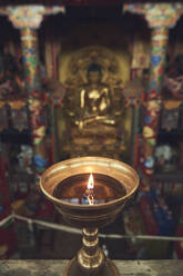 High angle of burning candle in candlestick lit for prayer in holy place in Buddhist temple in China - ADSF18309