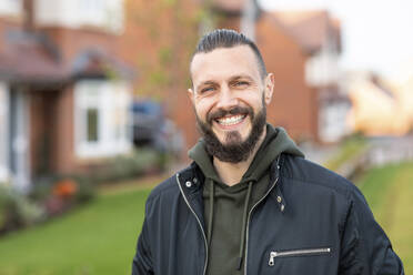 Happy bearded man standing in front yard - WPEF03707