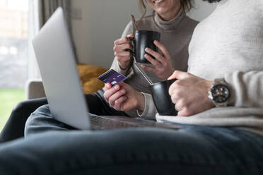 Ehepaar benutzt Kreditkarte beim Online-Einkauf über Laptop zu Hause - WPEF03718