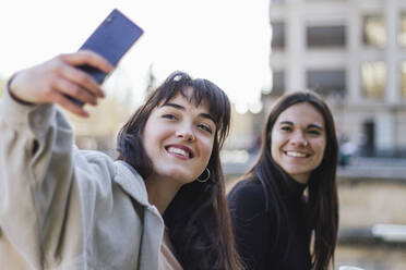 Glückliche junge Frau nimmt Selfie weiblichen Freund beim Sightseeing - MGRF00067
