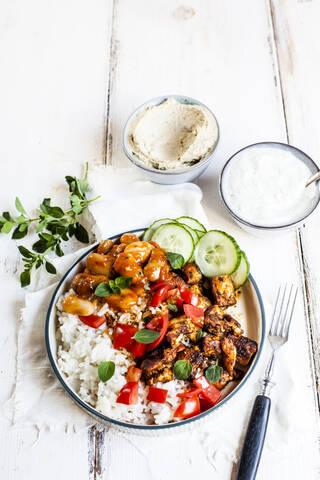 Bowl of Greek gyro with rice, fava beans, halloumi cheese, tomatoes and cucumbers stock photo