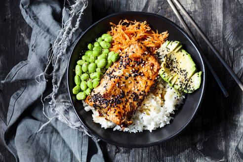 Bowl of teriyaki salmon with rice, carrot salad, edamame beans, avocado and sesame seeds - SBDF04442