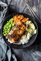 Bowl of teriyaki salmon with rice, carrot salad, edamame beans, avocado and sesame seeds - SBDF04443