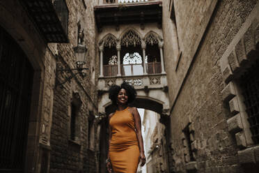 Smiling woman standing against arch in city, Barcelona, Spain - GMLF00851