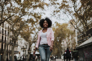 Carefree woman walking on street in city - GMLF00856