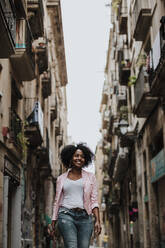 Smiling thoughtful woman walking in city - GMLF00857