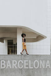 Mature woman walking on retaining wall with Barcelona text - GMLF00868