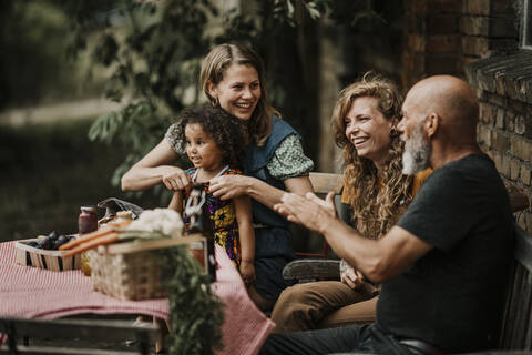 Smiling friends talking while sitting at backyard stock photo