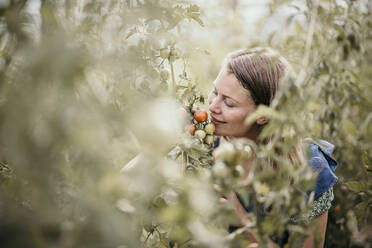 Frau lächelt und riecht an der Ernte in einer Pflanze - MJRF00315