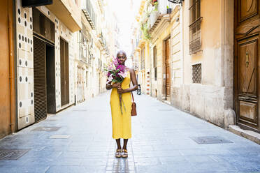 Frau mit leerem Blick hält Blumen auf der Straße in der Stadt - RCPF00444